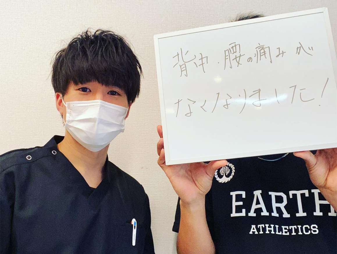 感謝の手紙を持つ患者と整体師が治療室でピースサインをしている様子